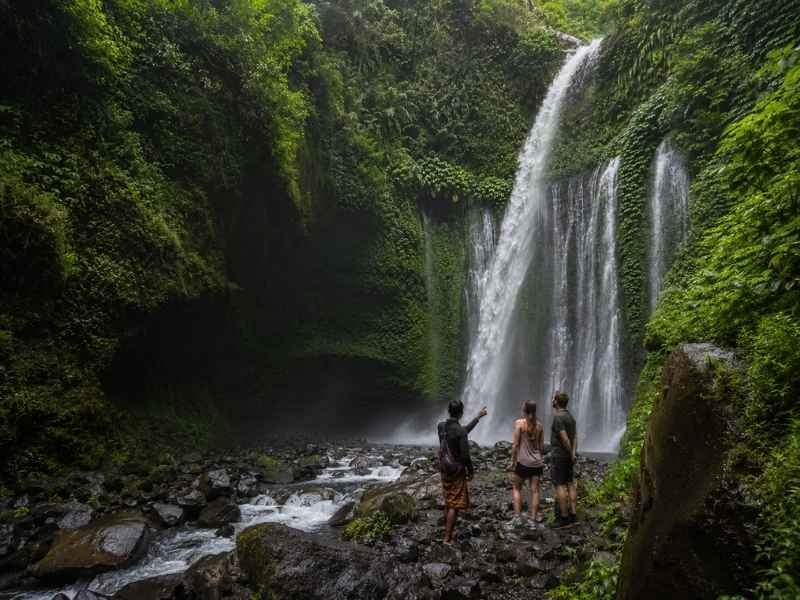 Couple listening to a local guide beside Tiu Kelep Waterfall