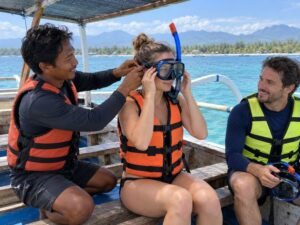 Local guide helping travelers fit snorkeling masks aboard a boat